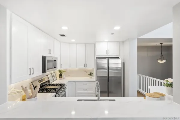 a kitchen with stainless steel appliances kitchen island granite countertop a refrigerator and a sink