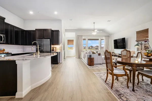 a kitchen with stainless steel appliances a dining table chairs refrigerator and microwave