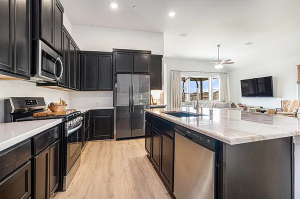 a kitchen with stainless steel appliances granite countertop a stove top oven a sink dishwasher a refrigerator and a oven with wooden floor