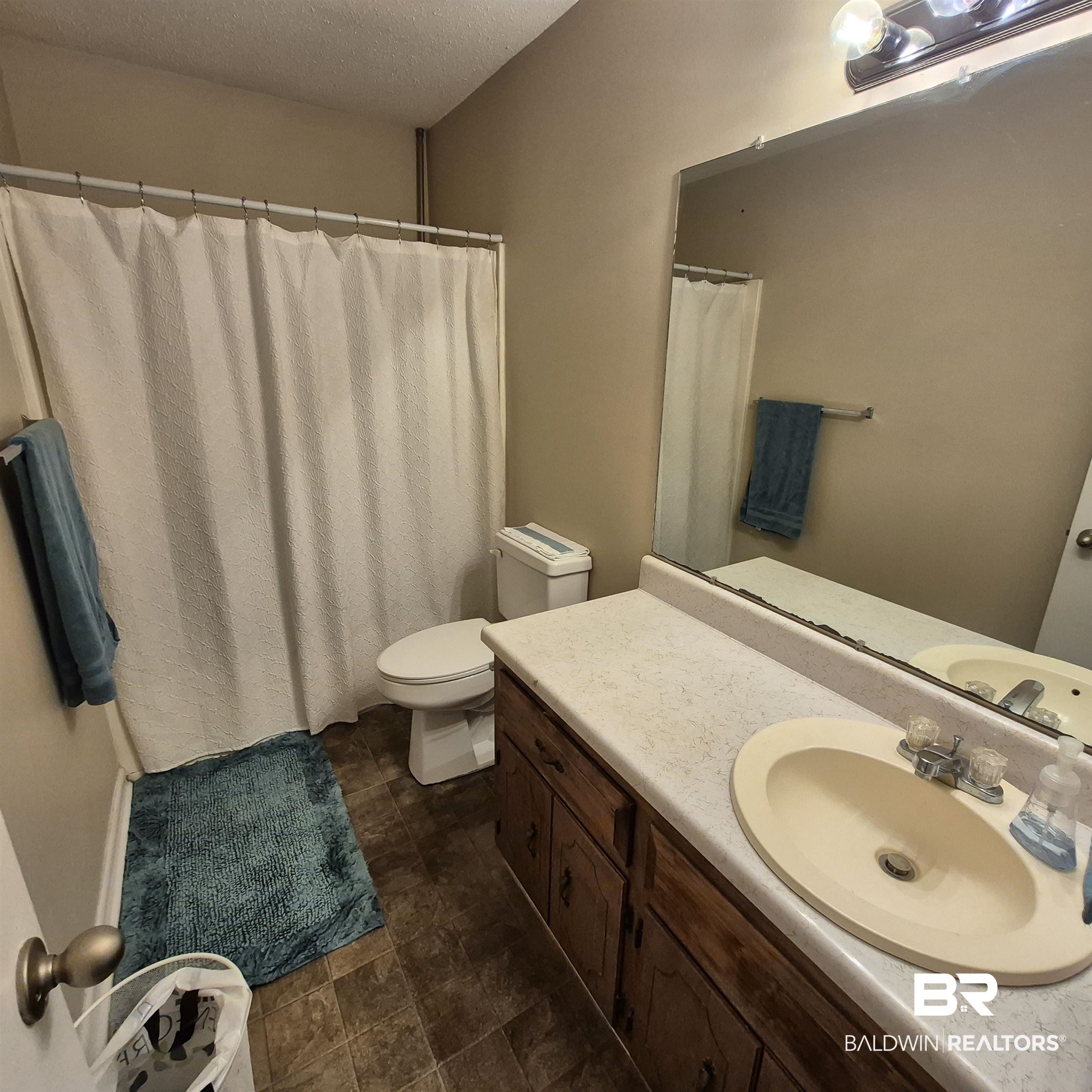 721 Perryman Street Evergreen, AL 36401 - Photo 17 of 26 Bathroom with vanity, a shower with curtain, and a textured ceiling