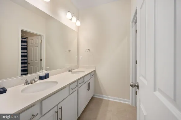 a spacious bathroom with a double vanity sink a mirror and a bathtub