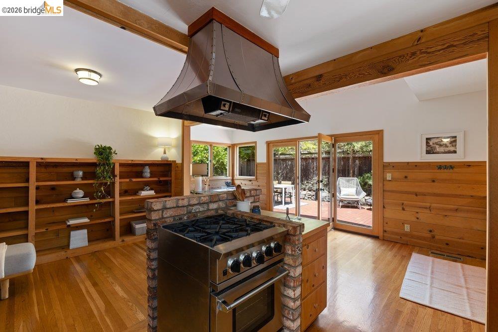 287 Purdue Avenue Kensington, CA 94708 - Photo 26 of 60 Stainless steel range with a custom metal hood, brick island base, wood-finish flooring, and exposed wood ceiling beams