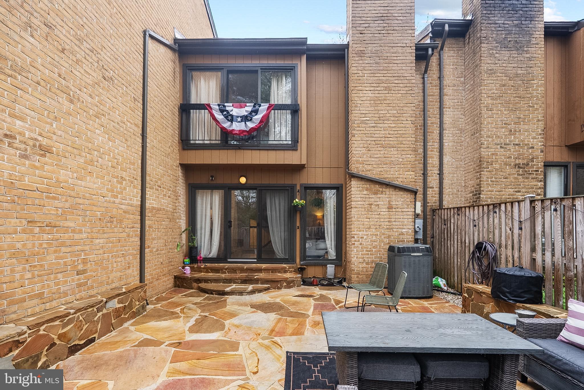 9060 Blarney Stone Drive Springfield, VA 22152 - Photo 43 of 47 a view of a brick house with a chairs and table in a patio