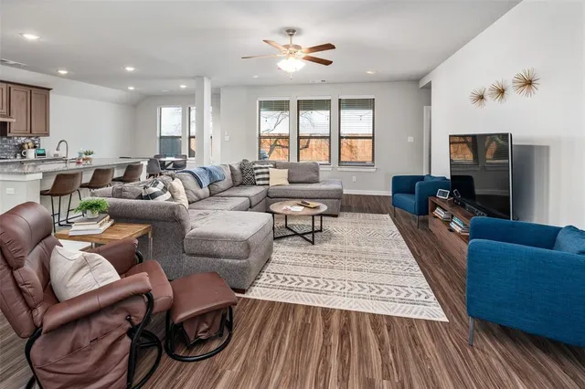 a living room with furniture a flat screen tv and kitchen view