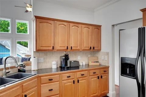 a kitchen with stainless steel appliances granite countertop a sink a refrigerator a stove and white cabinets with wooden floor