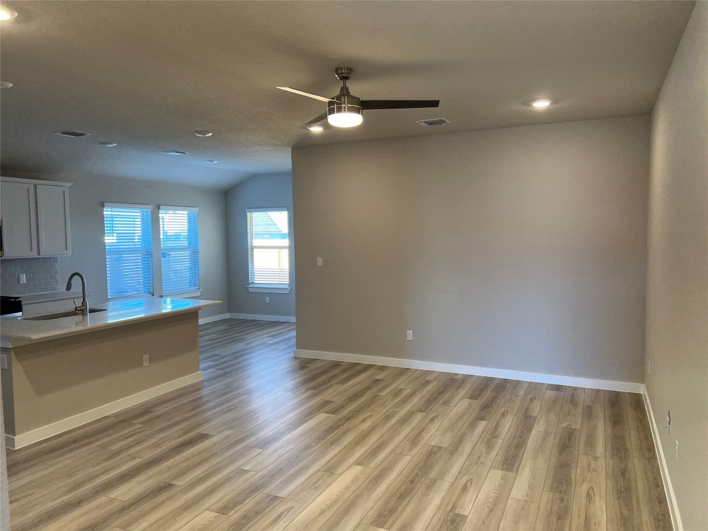 404 Coda Crossing Georgetown, TX 78633 - Photo 2 of 15 Kitchen with a kitchen island with sink, recessed lighting, white cabinetry, light wood finished floors, and a ceiling fan