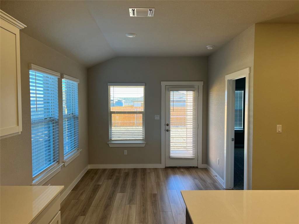 404 Coda Crossing Georgetown, TX 78633 - Photo 4 of 15 Unfurnished dining area featuring dark wood-type flooring, healthy amount of natural light, and vaulted ceiling