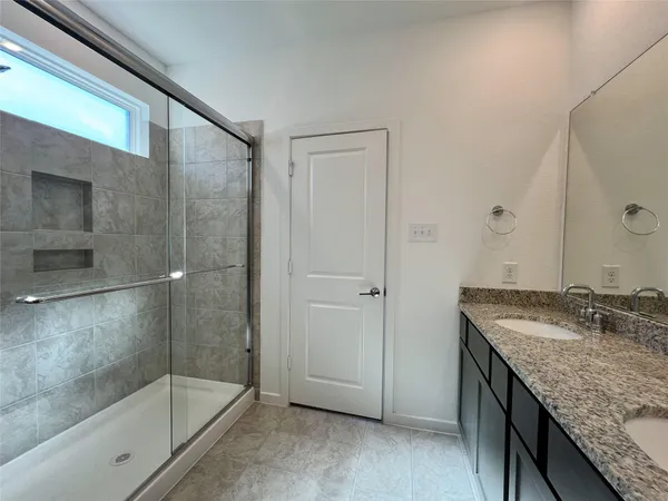 a bathroom with a granite countertop sink a mirror and shower