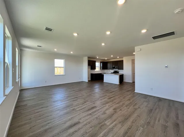 a view of empty room with kitchen and window