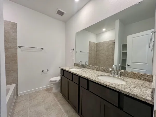 a bathroom with a granite countertop sink a toilet and a large mirror