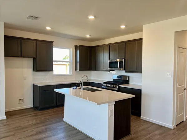 a kitchen that has a sink a microwave a stove and a counter top space