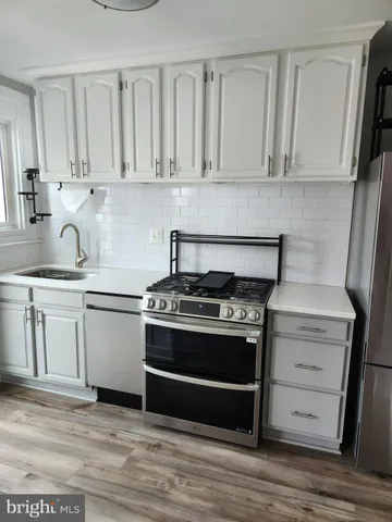 a kitchen with white cabinets and appliances