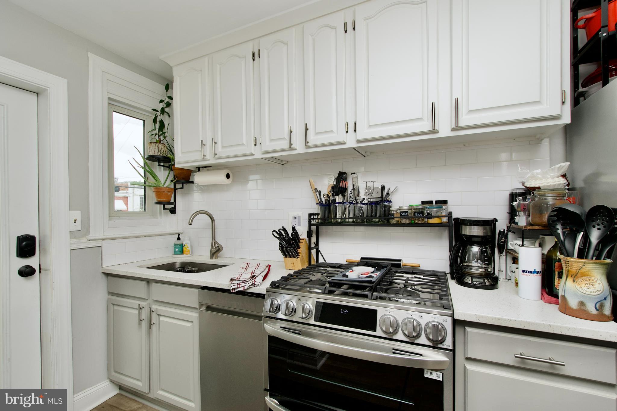1702 Lang Place Northeast Washington, DC 20002 - Photo 14 of 36 a kitchen with granite countertop white cabinets and stainless steel appliances