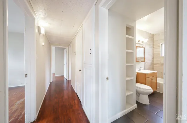 an empty room with wooden floor fan and windows
