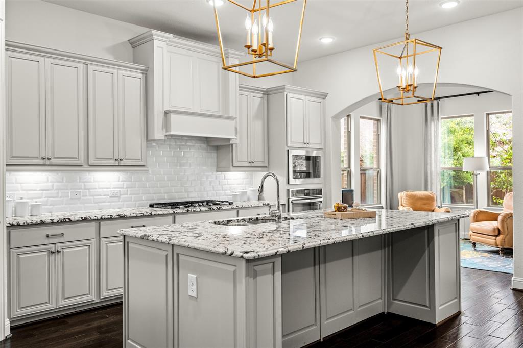 a kitchen with stainless steel appliances granite countertop a sink a stove and a wooden floors