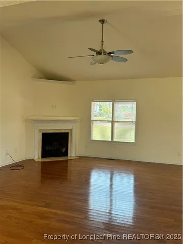 a view of empty room with wooden floor and fireplace