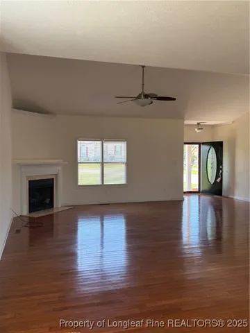 a view of an empty room with window and wooden floor