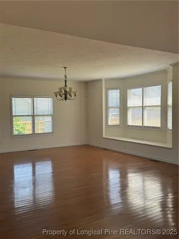 a view of an empty room with window and wooden floor
