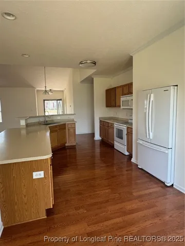 a living room with stainless steel appliances kitchen island granite countertop a refrigerator a stove top oven and a sink