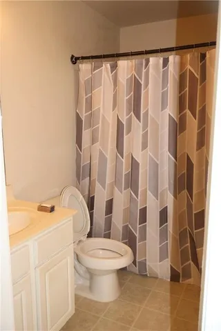 a white toilet sitting next to a white sink and a shower curtain
