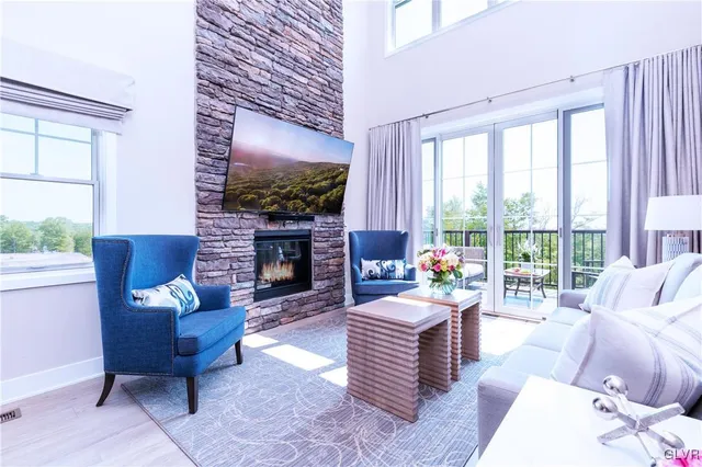 a living room with furniture a fireplace and a floor to ceiling window
