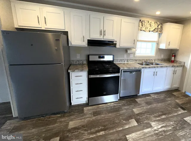 a kitchen with granite countertop a refrigerator stove top oven and sink