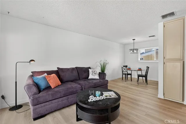 a living room with furniture and a dining table with wooden floor