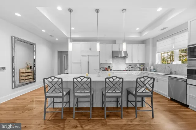 a kitchen with stainless steel appliances granite countertop a dining table chairs sink and cabinets