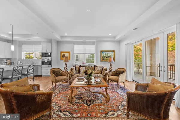 a living room with furniture large windows and wooden floor
