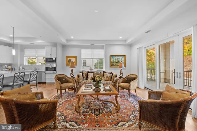 a living room with furniture large windows and wooden floor
