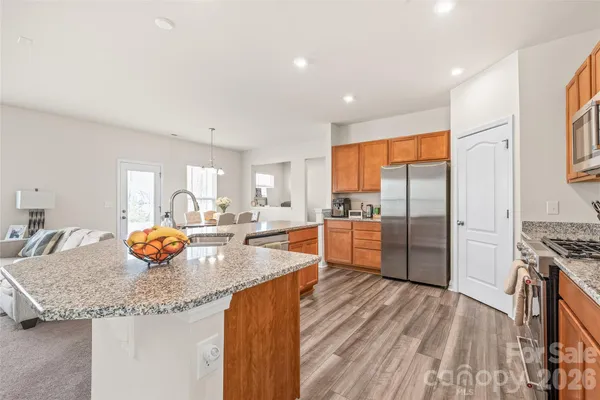 a kitchen with granite countertop a stove a sink and a refrigerator