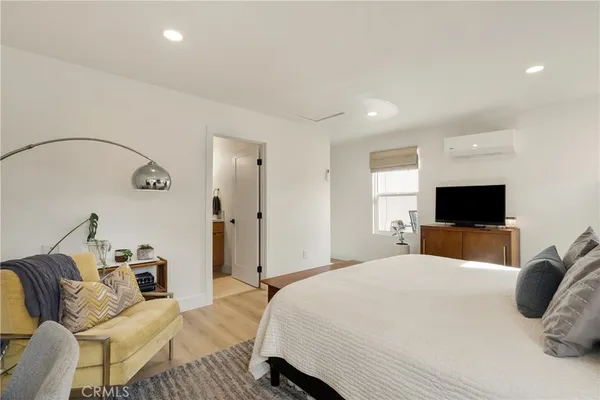 a bedroom with a bed a couch and a flat screen tv