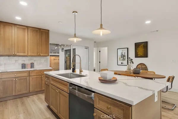 a kitchen with stainless steel appliances granite countertop a sink a stove a dining table and chairs with wooden floor