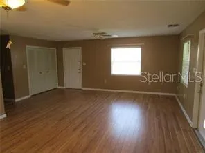 an empty room with wooden floor and windows