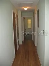 a view of a hallway with wooden floor and a bathroom