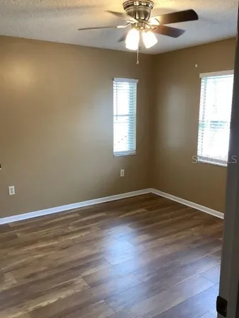 a view of an empty room with wooden floor and a window