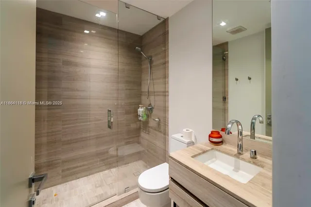 a bathroom with a granite countertop sink a toilet and shower