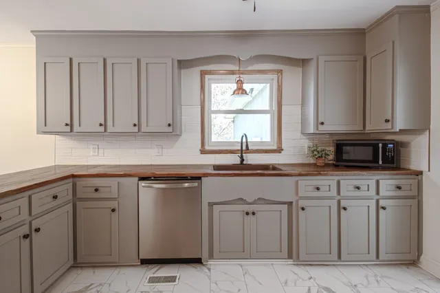 a kitchen with cabinets appliances a sink and a window