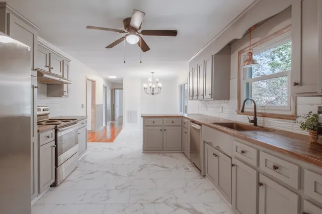 a large kitchen with granite countertop a stove a sink a refrigerator and a granite counter tops