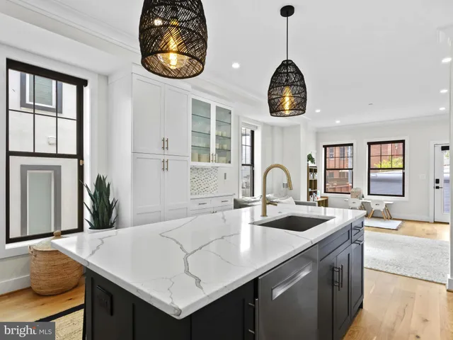 a kitchen with stainless steel appliances granite countertop a sink a stove and a dining table with wooden floor