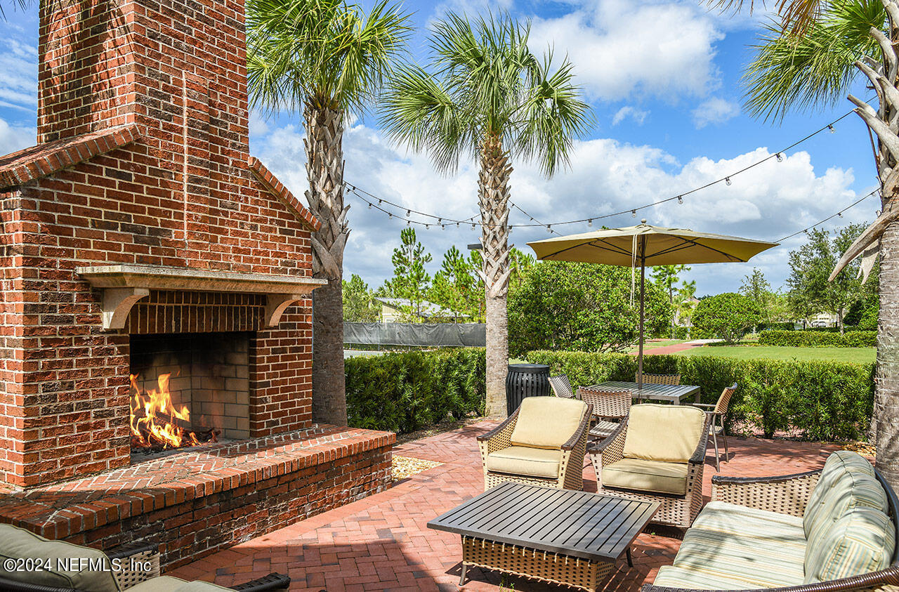 64 Cordelle Street St. Johns, FL 32259 - Photo 22 of 58 a view of a patio with a table and chairs under an umbrella with a fire pit and potted plants