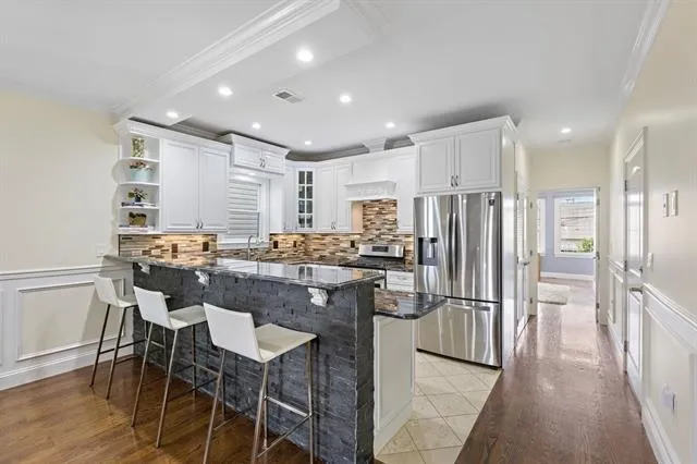 a kitchen with kitchen island granite countertop a refrigerator and a stove top oven