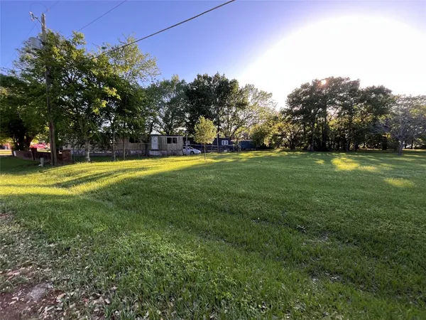 a view of a big yard with a fountain and large trees