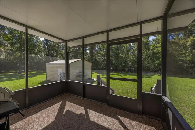 a view of an empty room with wooden floor and a large window