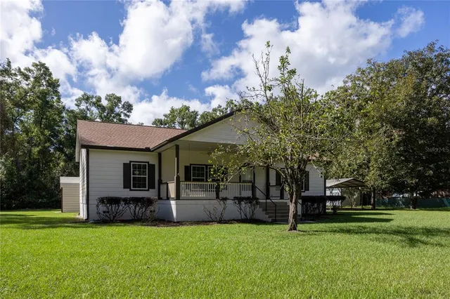 a view of a house with a big yard and a large tree