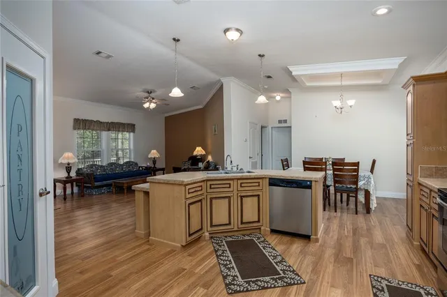 a kitchen with a sink a stove and chairs with wooden floor