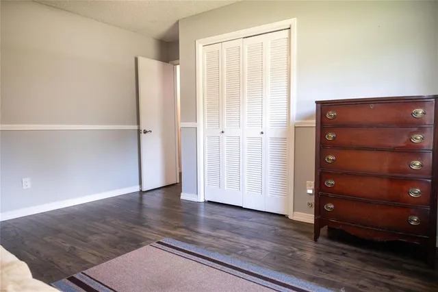 an empty room with wooden floor closet and windows
