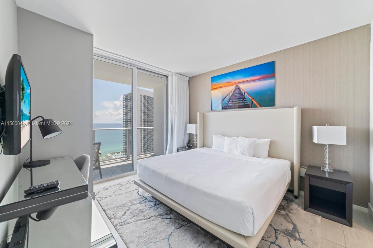 4010 South Ocean Drive, Unit R2505 Hollywood, FL 33019 - Photo 14 of 25 a bedroom with a bed and a lamp next to a window