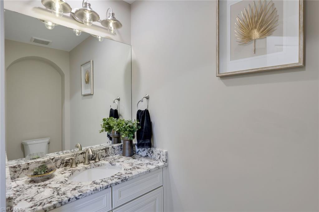 16445 Carrara Way, Unit 202 Naples, FL 34110 - Photo 17 of 35 a bathroom with a granite countertop sink a large mirror and vanity
