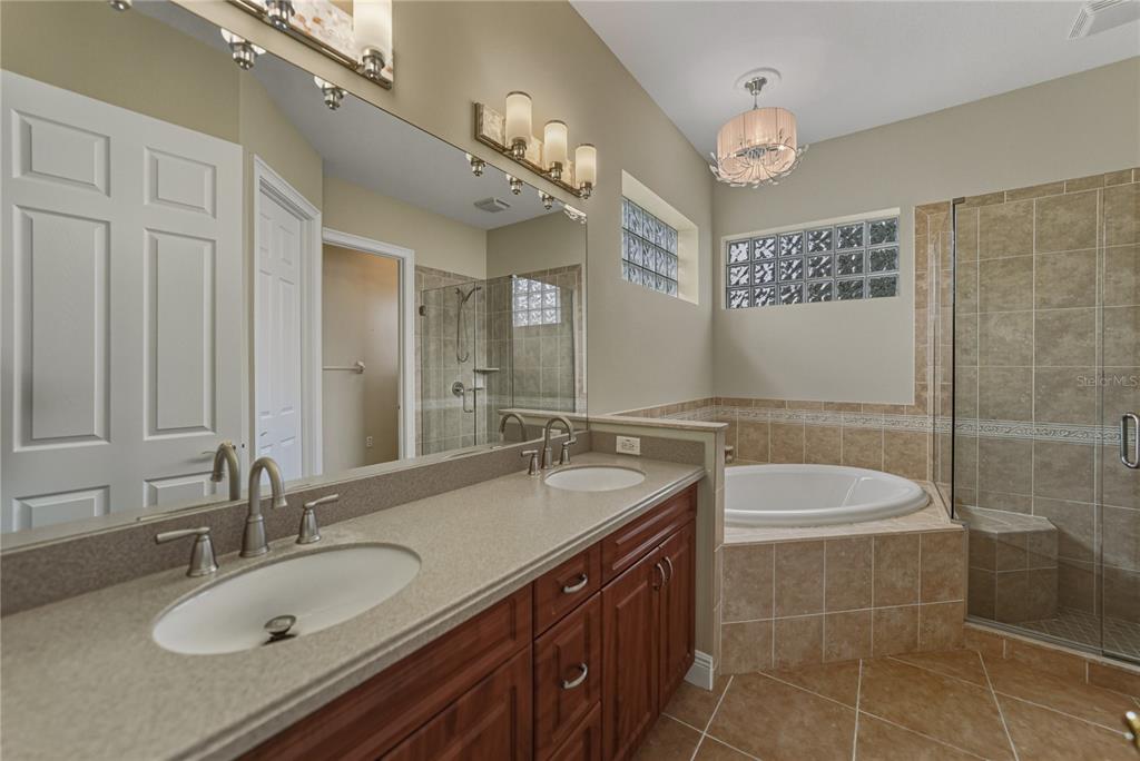 8725 Mississippi Run Spring Hill, FL 34613 - Photo 33 of 72 a bathroom with a granite countertop double vanity sink a mirror and a bathtub